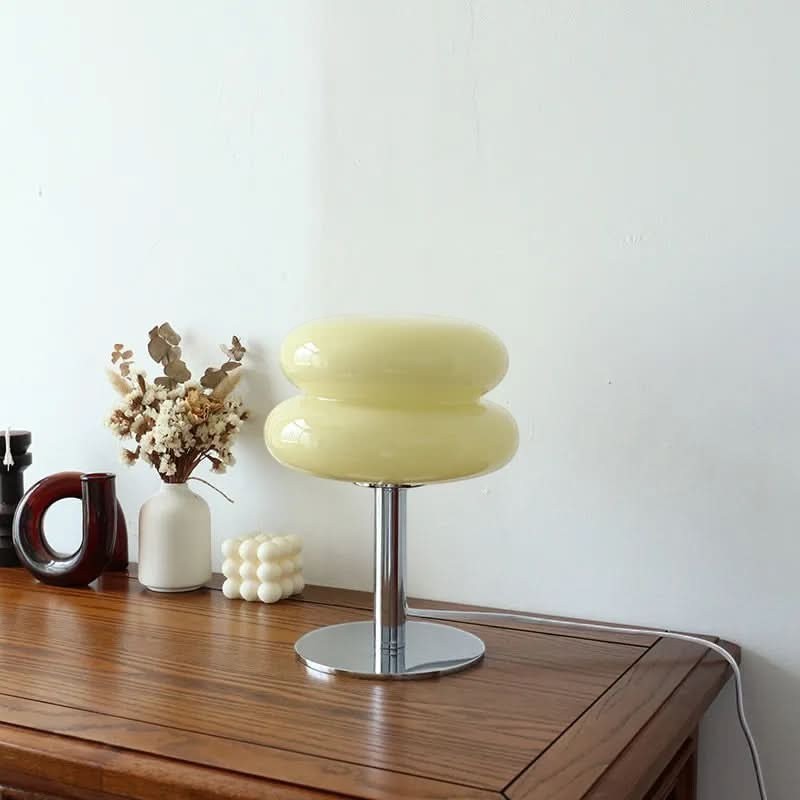 Lampe de table Dimoree en verre soufflé jaune pâle avec base en métal chromé sur une table en bois